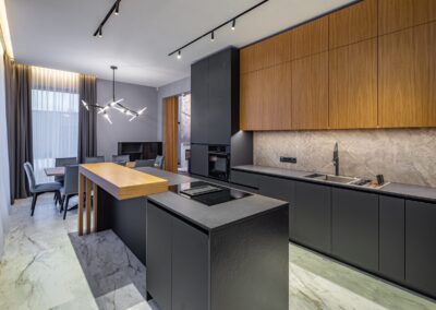 A modern kitchen with black cabinets and marble counter tops.