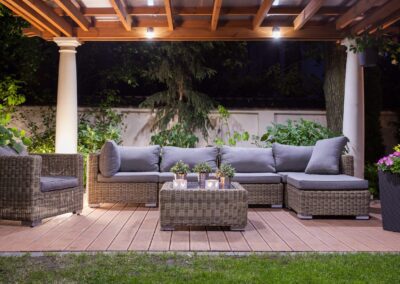 A wicker furniture set on a wooden deck at night.