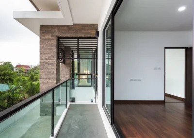 A balcony with glass railings and wooden flooring.